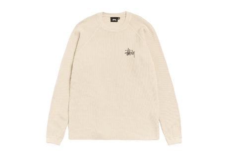 A cream-colored ribbed knit crewneck sweater with a small black Stüssy logo on the left chest, displayed flat against a solid white background.