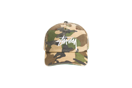 A Stussy camouflage trucker cap with a white embroidered logo on the front, set against a plain white background.