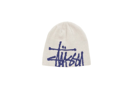 An off-white knit beanie featuring a dark blue Stüssy logo embroidered across the front, set against a plain white background.