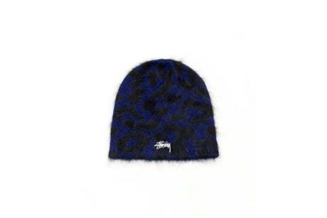 A Stussy fuzzy beanie hat featuring a dark blue and black leopard print pattern with a white embroidered Stussy logo on the front, set against a plain white background.