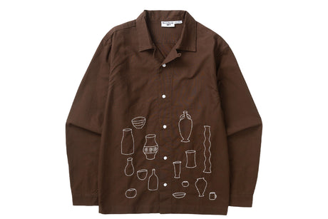 A brown long-sleeve button-up shirt with white line-art illustrations of various bottles and vessels printed on the front, displayed against a solid white background.