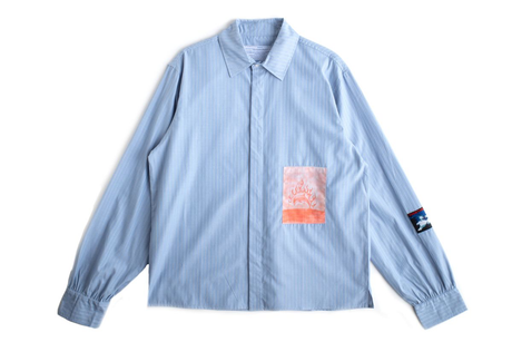 Light blue shirt with a patch on the sleeve against a white background