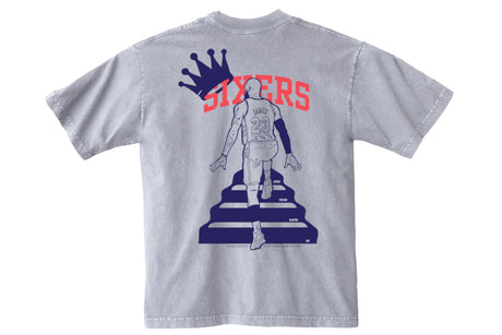 A light gray short-sleeve t-shirt shown from the back, featuring a distressed graphic of a basketball player on a podium with the word 'SIXTERS' in red and a blue crown.