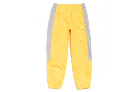 Yellow track pants with gray side panels on a white background