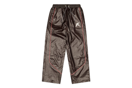 A pair of shiny dark brown pants with pink piping along the side seams and a small white graphic logo on the upper left leg, displayed flat against a white background.
