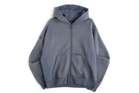 A faded slate blue-gray zip-up hoodie with a front kangaroo pocket and drawstring hood, laid flat against a white background.
