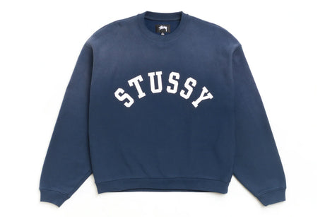 A navy blue crewneck sweatshirt with 'STUSSY' printed in white arched block letters across the chest, displayed flat against a plain white background.