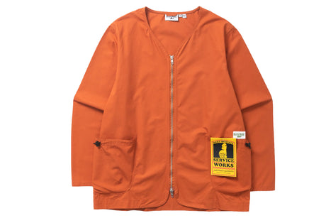 An orange zip-up utility jacket with a V-neck, featuring a yellow and black 'Stravky Works' patch on the lower right pocket, displayed flat against a white background.