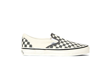 A single Vans slip-on platform sneaker featuring a black and white checkerboard pattern on the toe and heel, with a solid cream canvas upper and thick white platform sole.